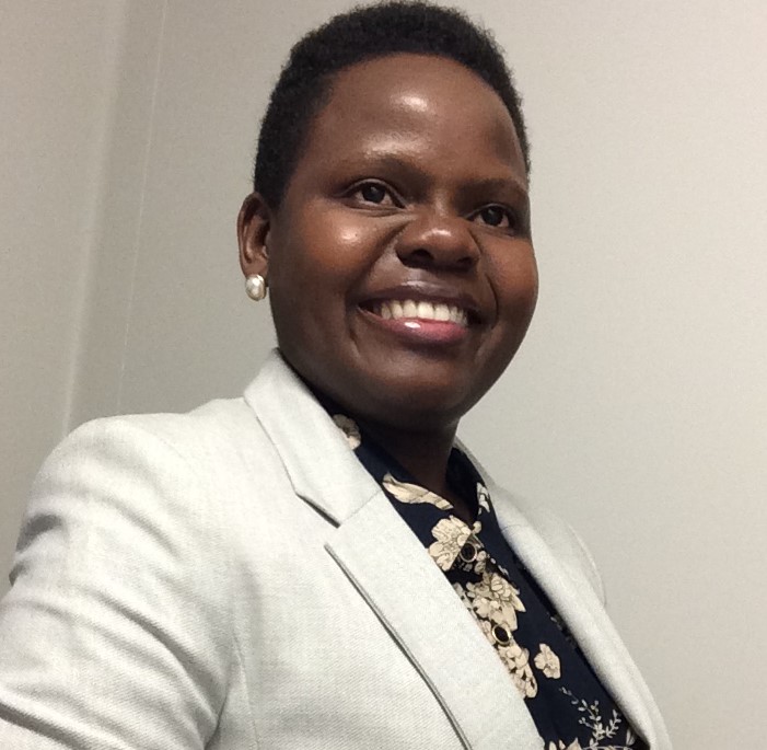 Photograph of Phylis Makurunje smiling while wearing a tan blazer and black shirt.